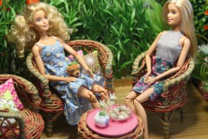 Barbie dolls sitting in the diy outdoor garden with their dog